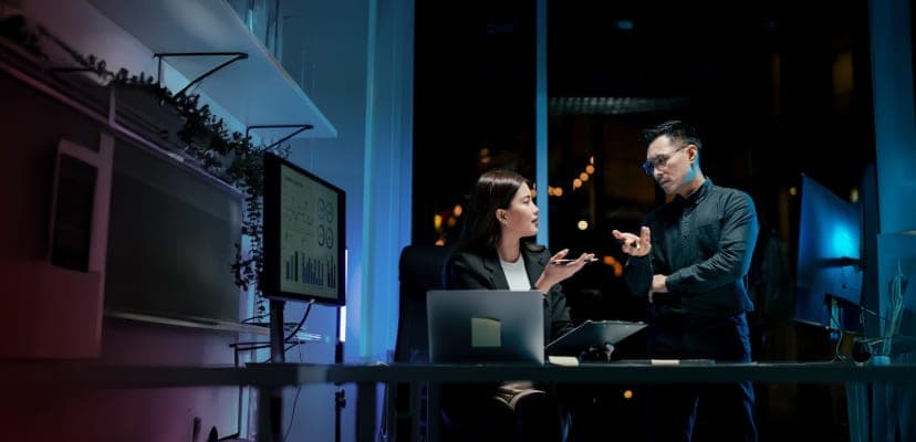 two people working at computer in dark, modern office