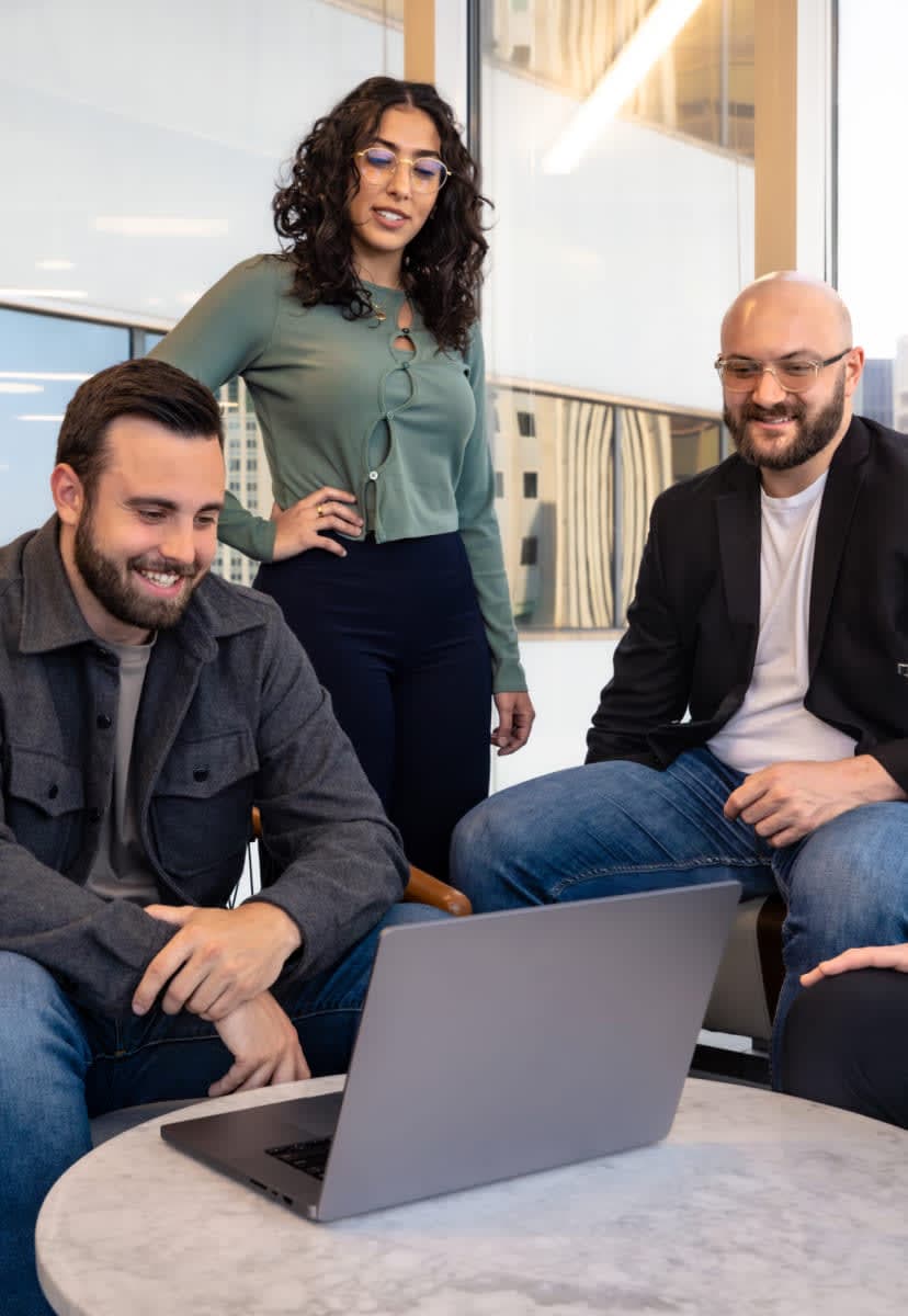 four happy team members working on a laptop together