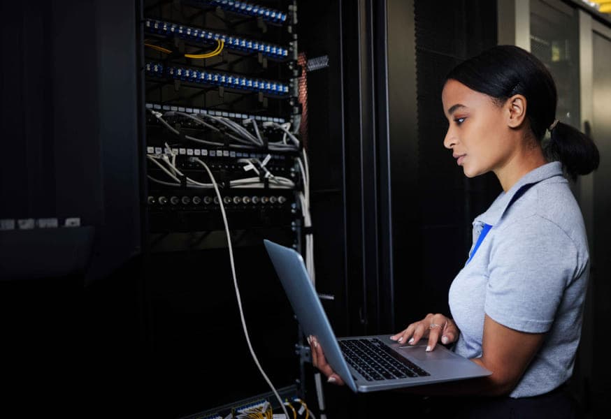 A woman holding a laptop connected to a server