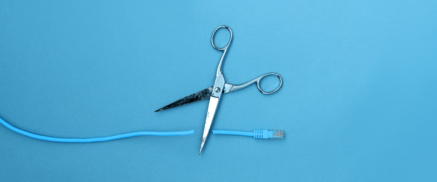A pair of scissors cutting an ethernet cable