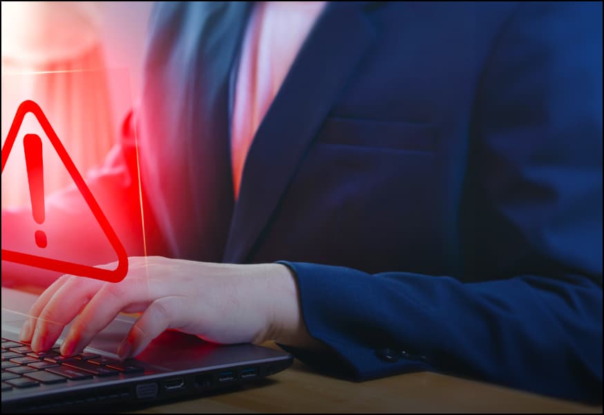 A person working on a laptop with a red warning triangle on the screen